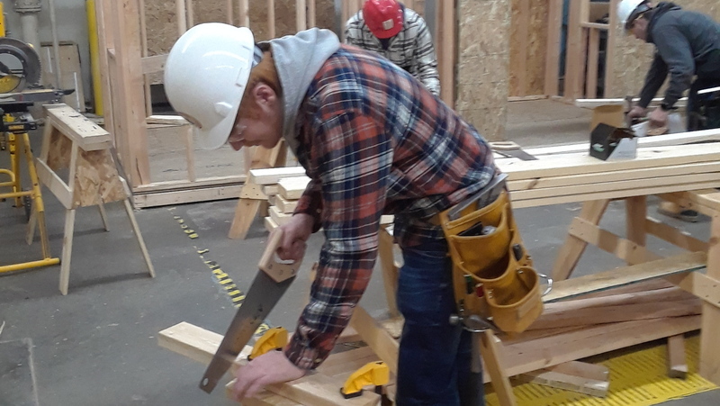 Construction student using a hand saw in the lab.